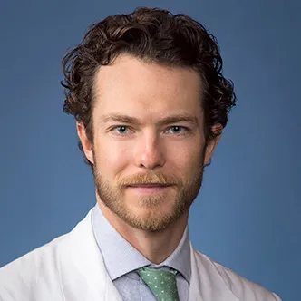 Dr. Kerr has short curly hair and a goatee, and is wearing a