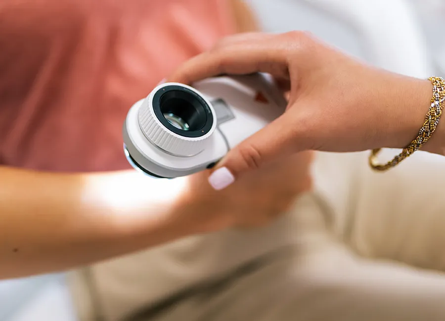 A doctor uses a loupe to examine a patient's arm.