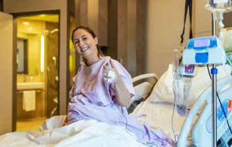 Young pregnant woman in the hospital ward doing a thumbs up