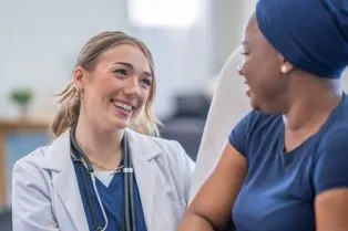 Female doctor laughing with Black female patient