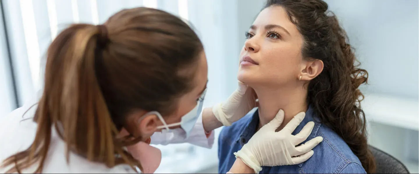 Endocrinologist examining throat of young woman in clinic