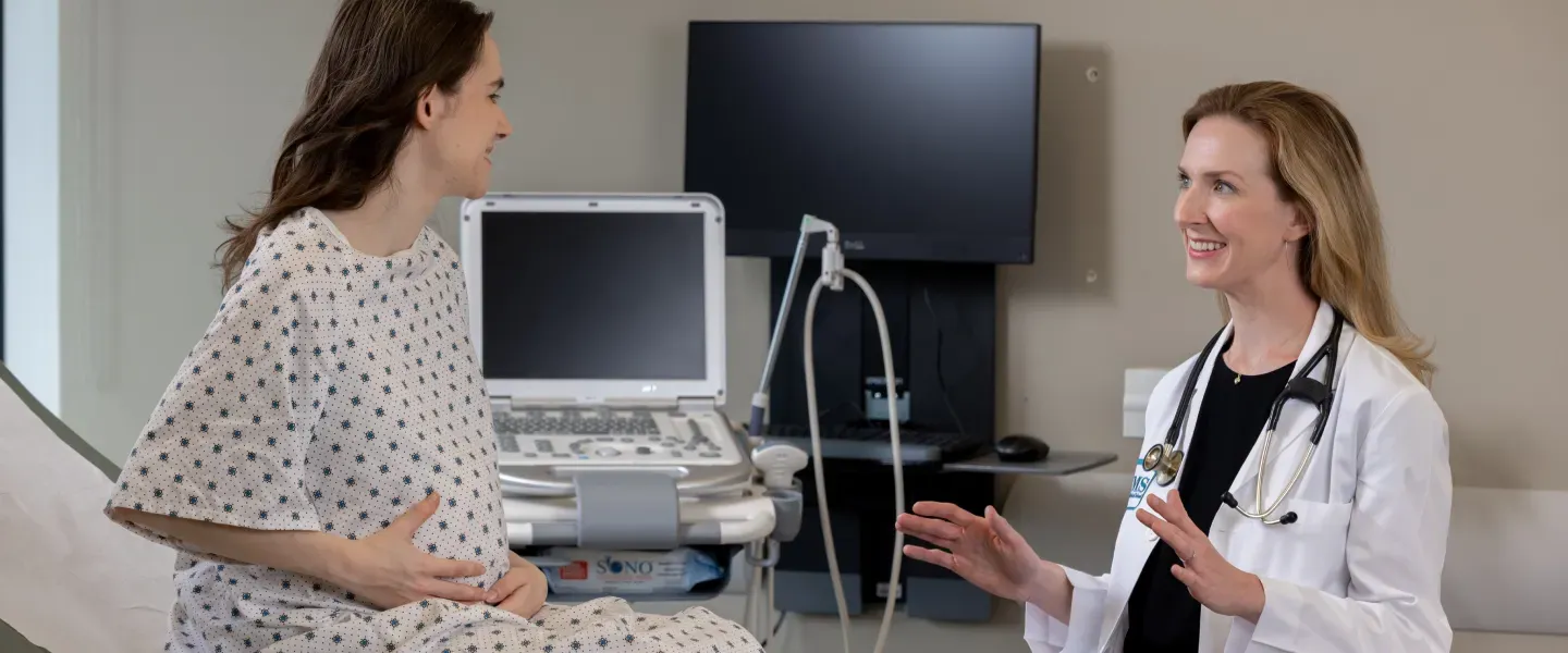 Dr. Robbins smiling with pregnant patient in a doctor's clin