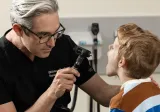 A doctor examines a child's throat using a light.