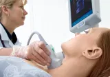A doctor examines a woman's thyroid using ultrasound