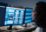 A female physician analyzing a brain scan over a laptop.