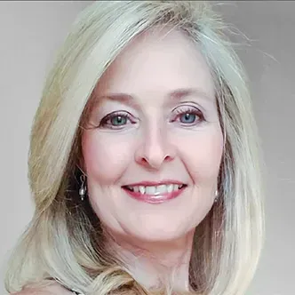 Dr. Caudill has long blonde hair, is wearing a white medical