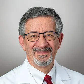 Dr. Kanaan has short gray hair, gray goatee and mustache, is