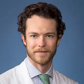 Dr. Kerr has short curly hair and a goatee, and is wearing a