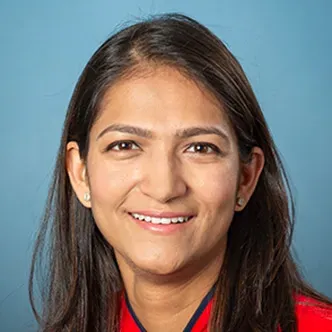 Dr. Patel has long, straight dark hair, is wearing a bright 