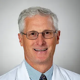 Dr. Sayles has short gray hair, is wearing glasses and a blu