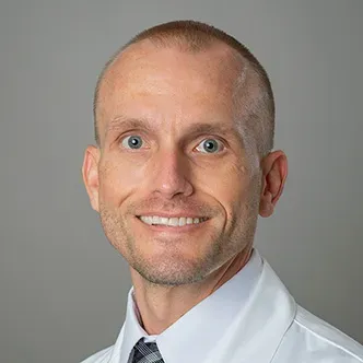 Dr. Davis has very short dark hair, is wearing a white dress