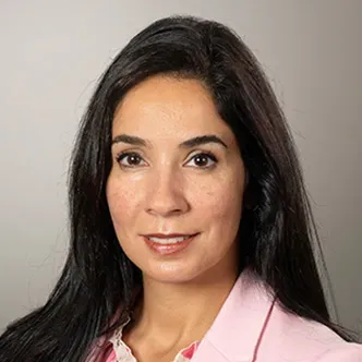 Dr. Saber has long dark hair, is wearing a multi-pink blouse