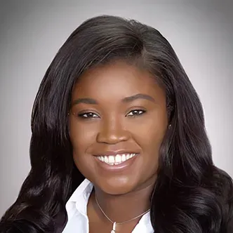 Dr. Cudjoe has long dark hair, is wearing a black jacket and