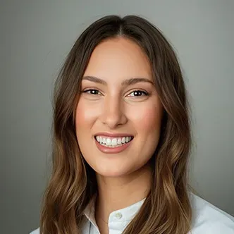 Dr. van Reesema has long brown hair, is wearing a white medical coat and is smiling at the camera