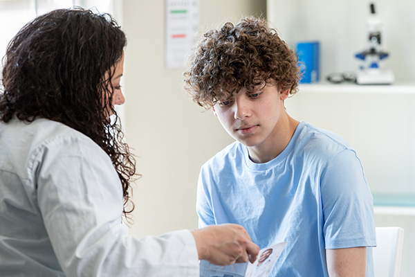 A doctor speaks to a teen boy about mental health.